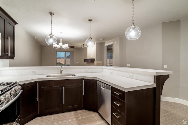kitchen featuring an inviting chandelier, a sink, light countertops, appliances with stainless steel finishes, and dark brown cabinets