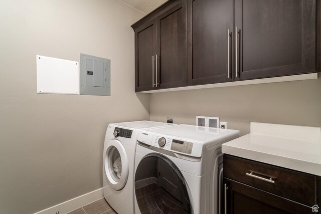 clothes washing area featuring electric panel, baseboards, washer and clothes dryer, and cabinet space