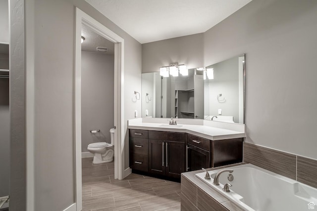 bathroom featuring toilet, a bath, vanity, and baseboards