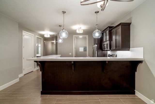 kitchen with stainless steel appliances, dark brown cabinetry, a breakfast bar, and light countertops