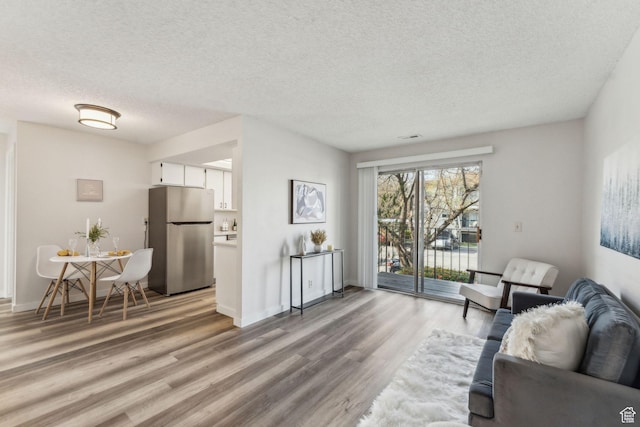 1039 E Quail Vista Ln Unit I, Salt Lake City, UT 84117 - living room with a textured ceiling, light wood finished floors, baseboards, and visible vents