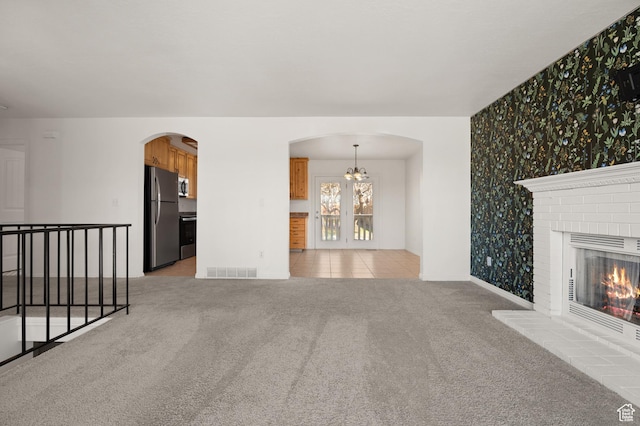 1705 E 2800 N, Layton, UT 84040 - unfurnished living room featuring visible vents, baseboards, arched walkways, wallpapered walls, and light colored carpet
