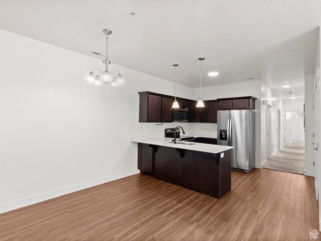 3679 W 1530 N Unit 102, Lehi, UT 84043 - kitchen featuring dark brown cabinets, a breakfast bar, appliances with stainless steel finishes, light countertops, and a sink