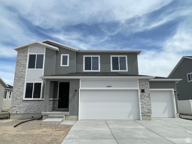 view of front of home with stone siding, a garage, driveway, and stucco siding