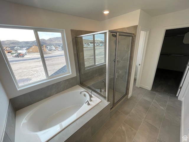bathroom featuring a walk in closet, a garden tub, a stall shower, and a mountain view