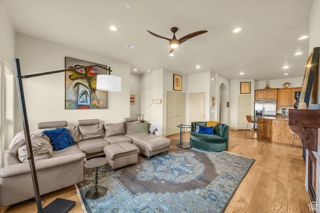 living area featuring recessed lighting, arched walkways, light wood-style floors, and ceiling fan