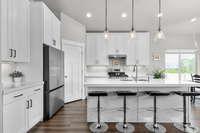 kitchen with a sink, a kitchen breakfast bar, under cabinet range hood, recessed lighting, and stainless steel appliances