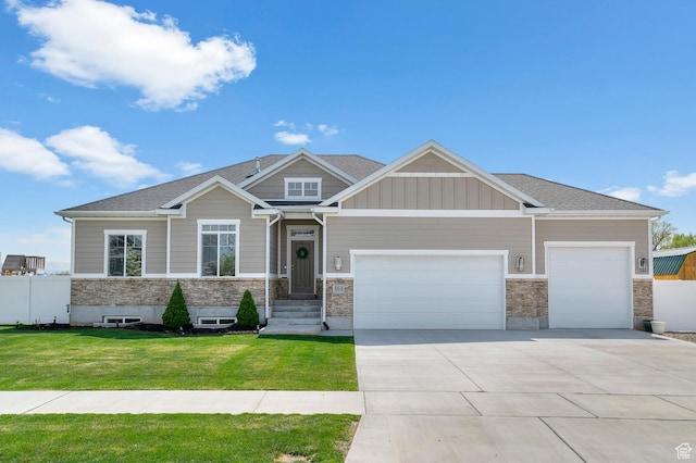 craftsman inspired home with a front yard, an attached garage, stone siding, fence, and concrete driveway