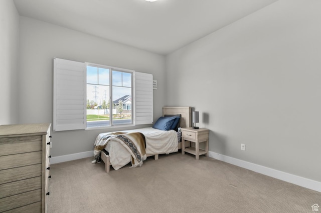 bedroom featuring baseboards and light colored carpet