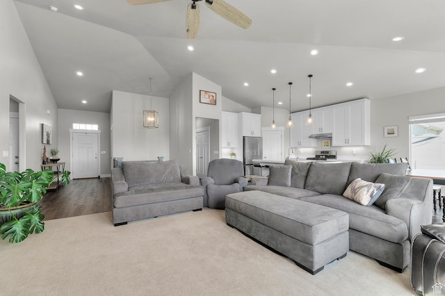 living area with light carpet, recessed lighting, light wood-style floors, ceiling fan, and high vaulted ceiling