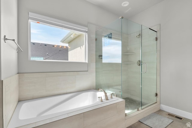bathroom with a shower stall, a garden tub, baseboards, and visible vents