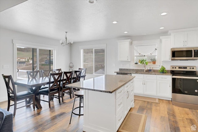 kitchen featuring a sink, a wealth of natural light, appliances with stainless steel finishes, and an inviting chandelier