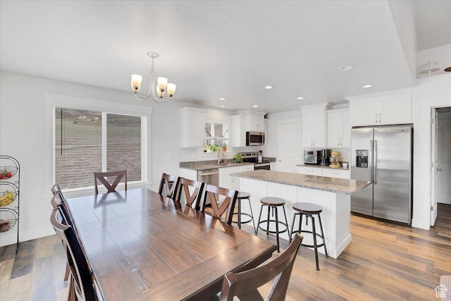 dining room with recessed lighting, an inviting chandelier, and wood finished floors