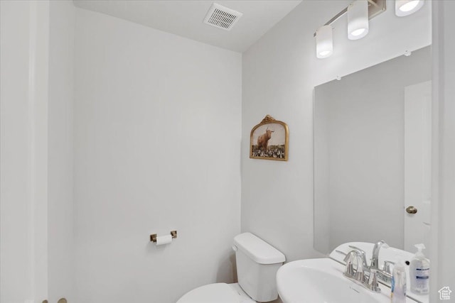 bathroom featuring toilet, a sink, and visible vents