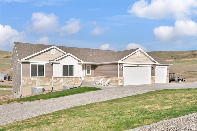 view of front facade featuring a front lawn, stone siding, a garage, and concrete driveway