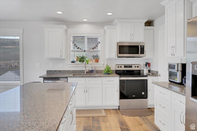 kitchen featuring a sink, light wood-style flooring, white cabinets, and stainless steel appliances