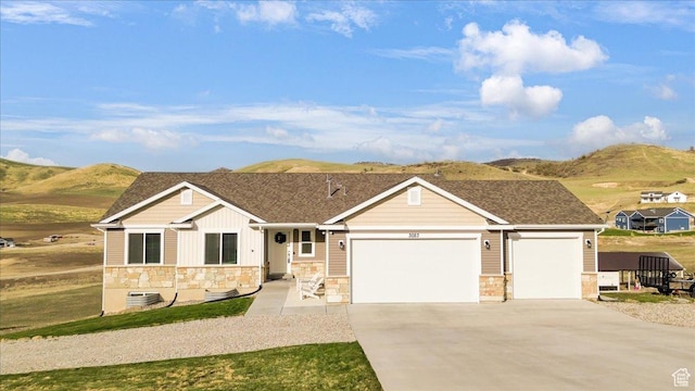 ranch-style house with an attached garage, a mountain view, driveway, and stone siding