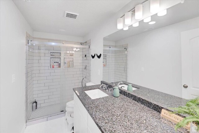 bathroom with visible vents, toilet, a stall shower, and vanity