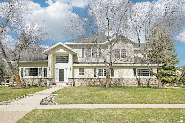 view of front of property with a front yard, stucco siding, stone siding, and a chimney