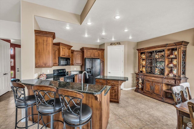 kitchen with a breakfast bar, a peninsula, brown cabinetry, black appliances, and a kitchen island