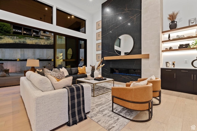 living area with light wood-style floors, a high ceiling, and a fireplace