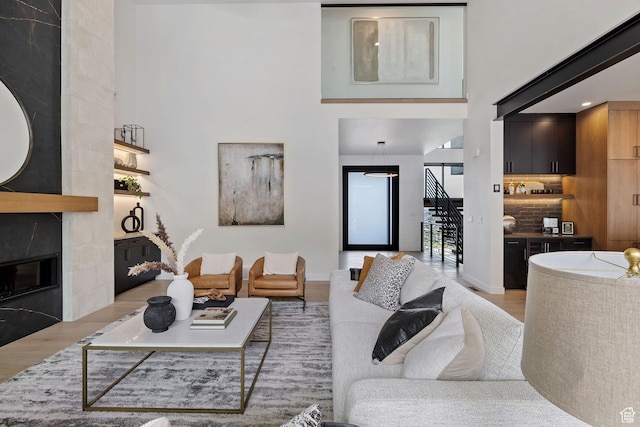 living area featuring stairway, a towering ceiling, wood finished floors, and a fireplace