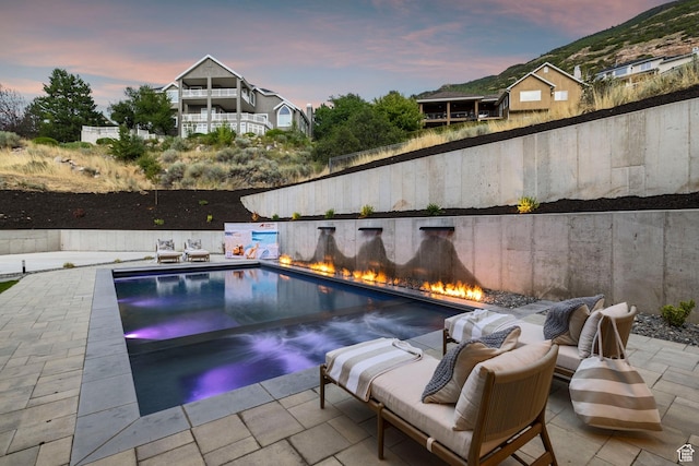 pool at dusk with a patio and a fenced backyard