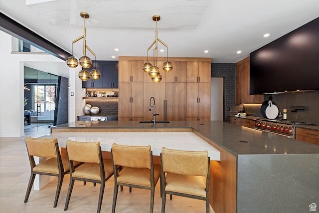 kitchen featuring tasteful backsplash, a sink, range with two ovens, and dark countertops