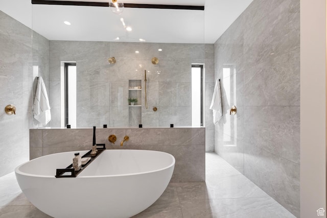 bathroom with a walk in shower, a freestanding tub, and tile walls