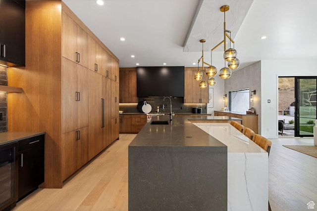 kitchen with light wood-style floors, a large island with sink, a sink, and modern cabinets