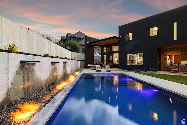 pool at dusk with a patio area, a fenced backyard, outdoor lounge area, and a fenced in pool