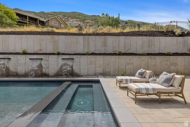 view of swimming pool featuring fence, a patio, a swimming pool, and a mountain view