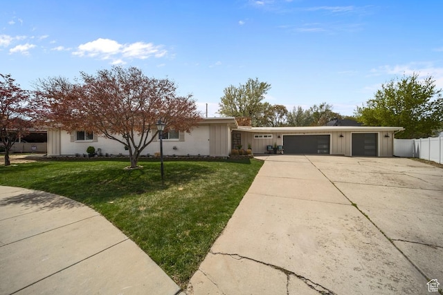 view of front facade featuring board and batten siding, a front yard, fence, an attached garage, and driveway