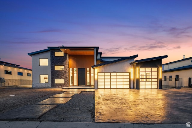 contemporary home with driveway, stone siding, and a garage
