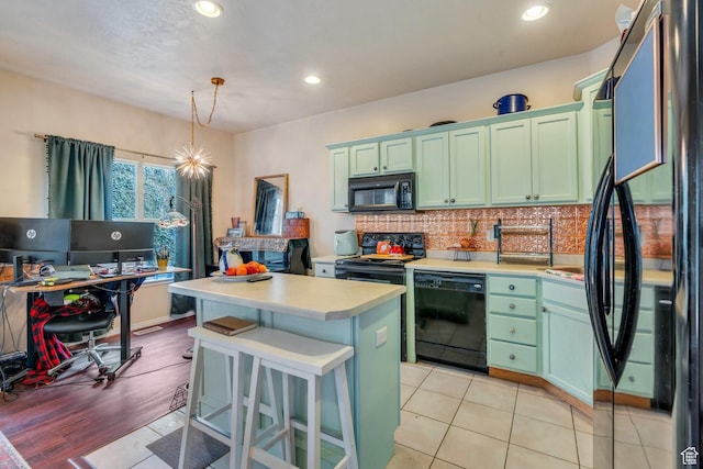 kitchen with tasteful backsplash, light countertops, black appliances, green cabinets, and a kitchen island
