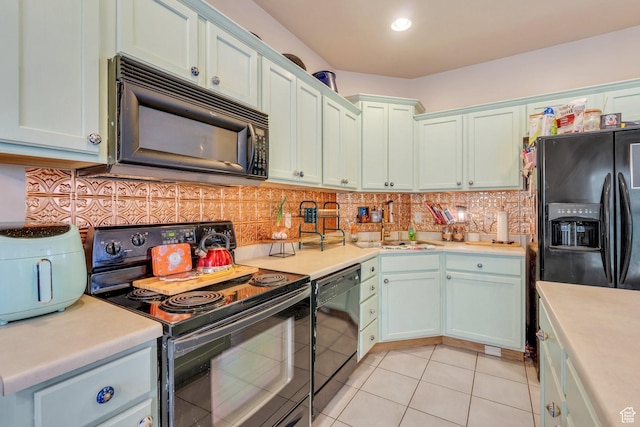 kitchen with a sink, light countertops, black appliances, and light tile patterned flooring