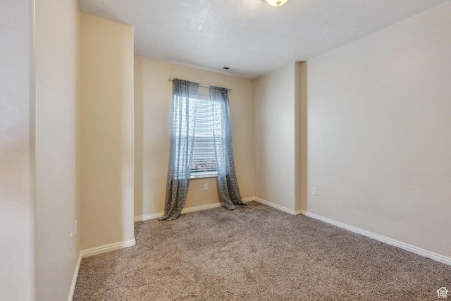 spare room with baseboards, carpet, and visible vents