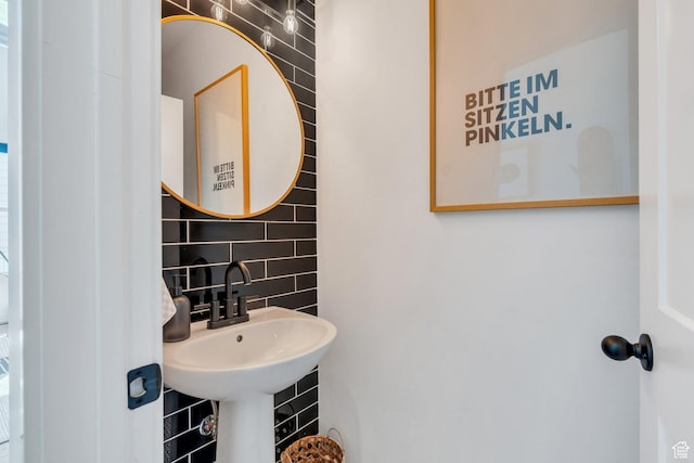 bathroom with decorative backsplash, a sink, and tile walls