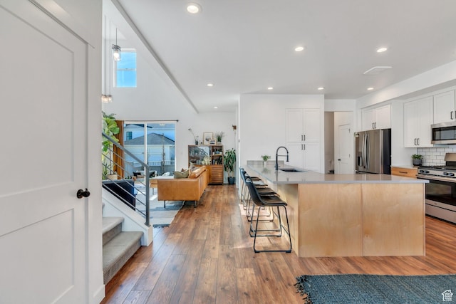 kitchen with light wood-style flooring, white cabinets, a kitchen bar, appliances with stainless steel finishes, and a sink