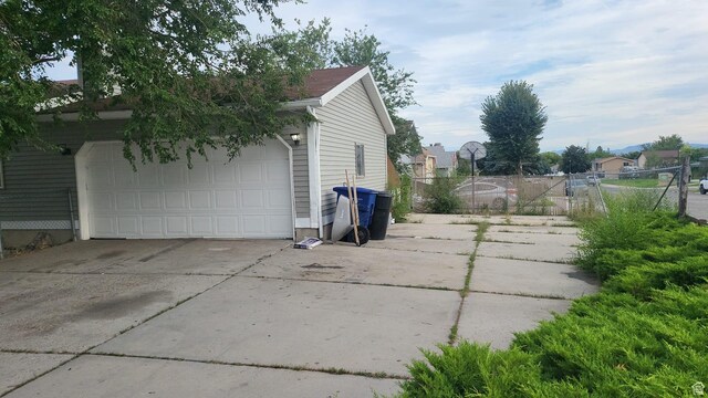 view of side of home featuring driveway, fence, and a garage