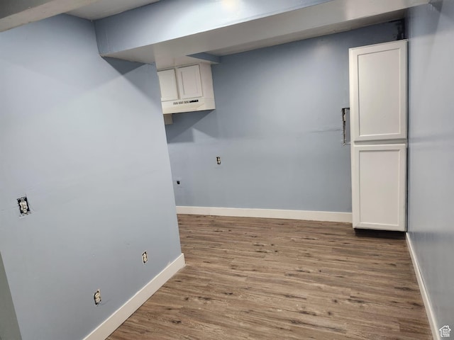 clothes washing area with baseboards and wood finished floors