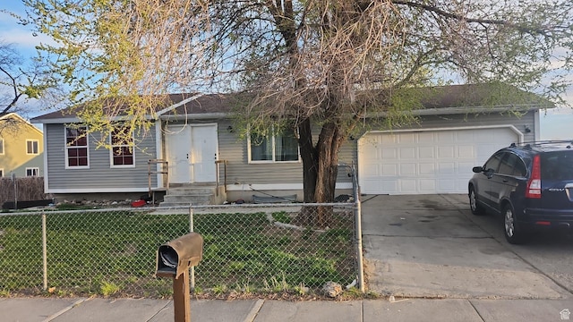 ranch-style home with entry steps, a garage, concrete driveway, a fenced front yard, and a front lawn