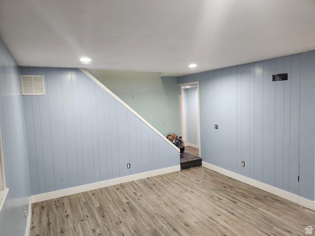 finished basement featuring recessed lighting, stairway, visible vents, and wood finished floors