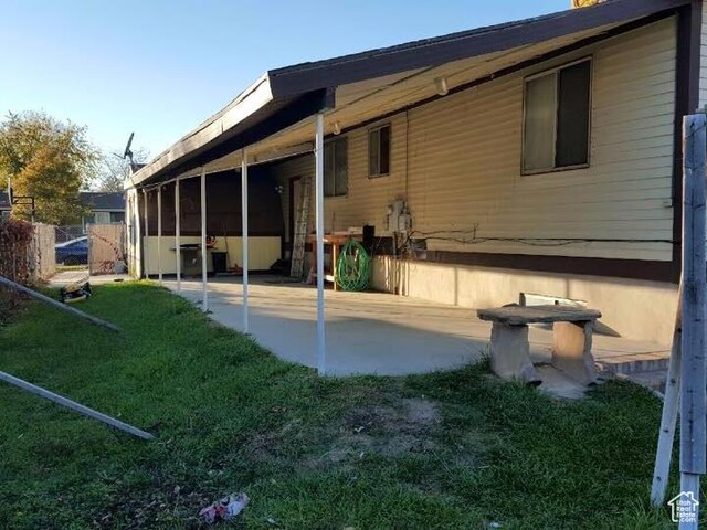 back of property featuring a patio, fence, an attached carport, and a lawn