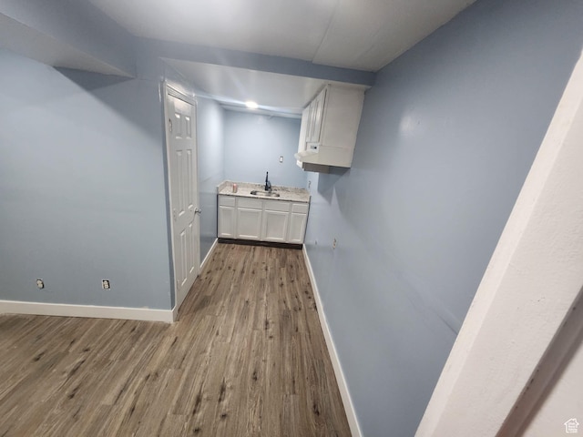 interior space featuring wood finished floors, a sink, and baseboards