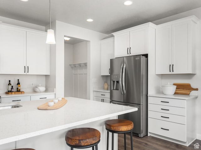 kitchen with stainless steel fridge with ice dispenser, white cabinetry, recessed lighting, a breakfast bar, and dark wood-style floors
