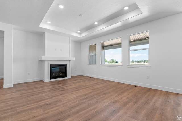 1489 E 820 N Unit 104, Salem, UT 84653 - unfurnished living room with a raised ceiling, wood finished floors, a glass covered fireplace, and recessed lighting