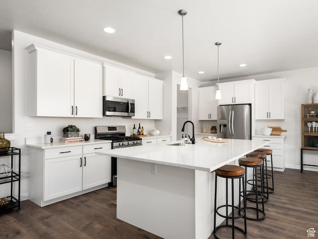 kitchen with a breakfast bar area, dark wood-type flooring, a sink, and appliances with stainless steel finishes