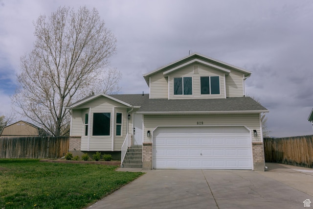 split level home with fence, a garage, and concrete driveway