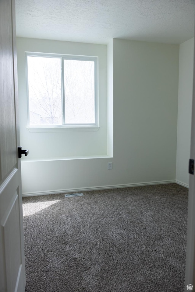 empty room featuring visible vents, baseboards, carpet, and a textured ceiling